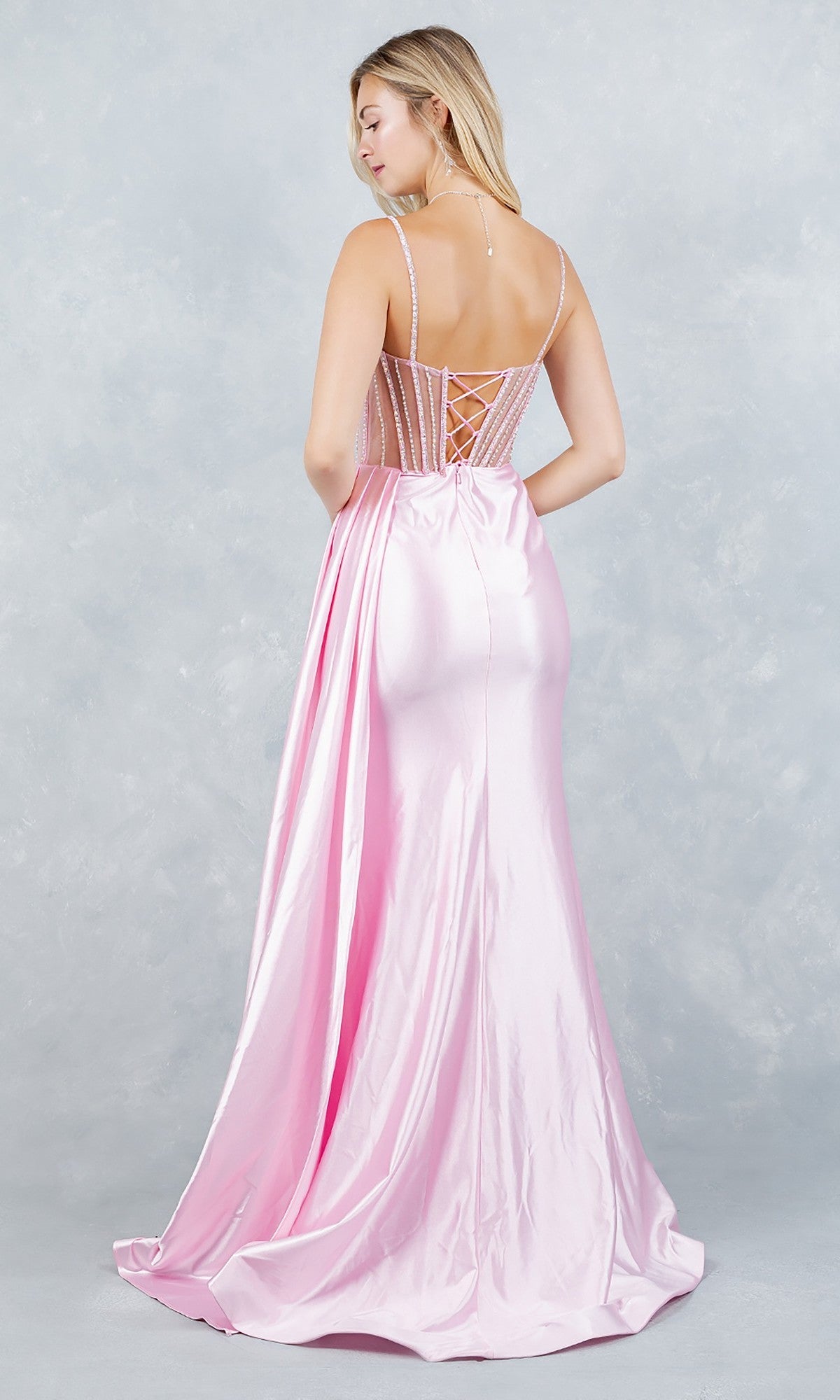A woman faces away, wearing the Cinderella Couture 8593J long prom dress in light pink satin with floral beading, thin straps, and a corset-style lace-up back, set against a light textured background.